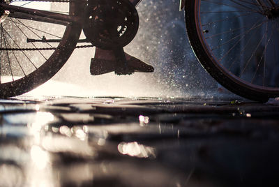 Low section of person riding bicycle on street in rainy season