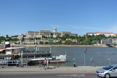 People by sea against buildings in city