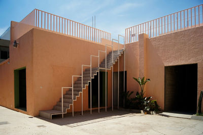 Regionalist house, painted pink with white ironwork staircase, a handrail is visible at the top