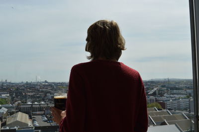 Rear view of man looking at city against sky