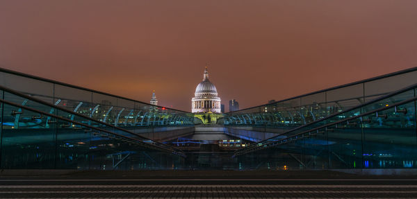 Illuminated bridge and buildings against sky at dusk