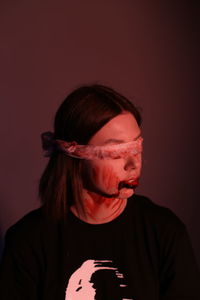 Close-up of injured woman with blindfolds against colored background