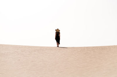 Young female tourist standing on sandy hill while exploring dunes of corralejo under cloudy sky in fuerteventura canary islands spain