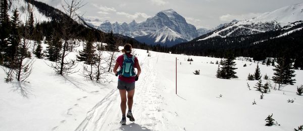 Rear view of woman walking on snowcapped mountains