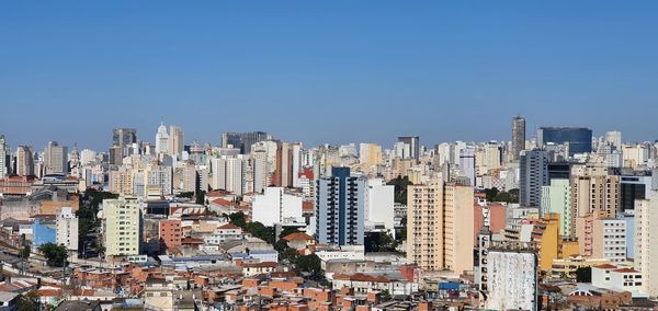 Aerial view of buildings in city against clear sky