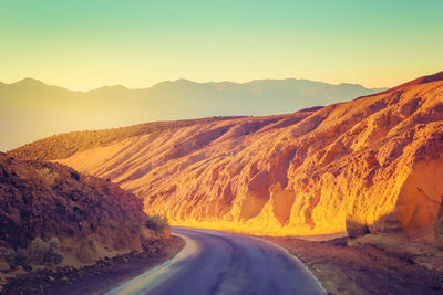 Road amidst desert against clear sky