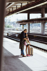 Full length of mother and daughter waiting at railroad station platform