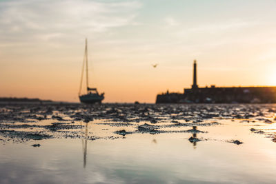 Sailboats in sea against sky during sunset