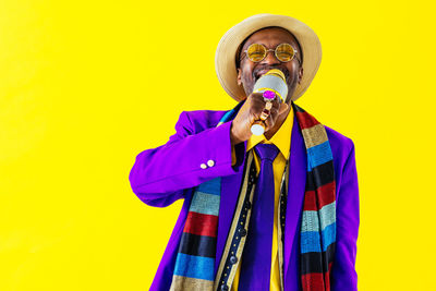 Man singing while standing against yellow background