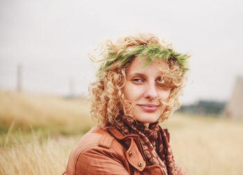 Portrait of smiling young woman standing on field against sky