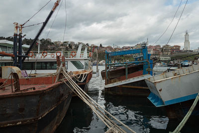 Boats in harbor against cloudy sky