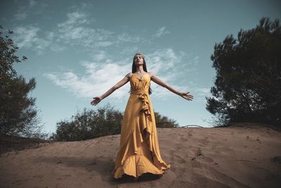 Woman with arms outstretched standing on sand