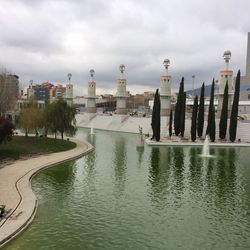 Reflection of buildings in lake against cloudy sky