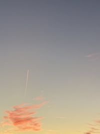 Low angle view of vapor trail in sky during sunset