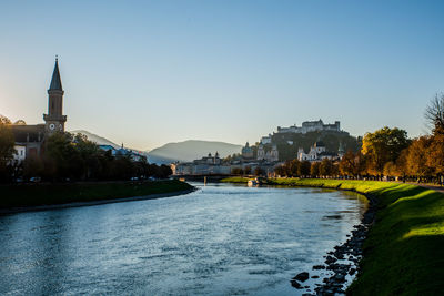 Scenic view of river by buildings against clear sky