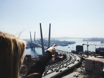 Rear view of woman on hill against sky pointing on a bridge