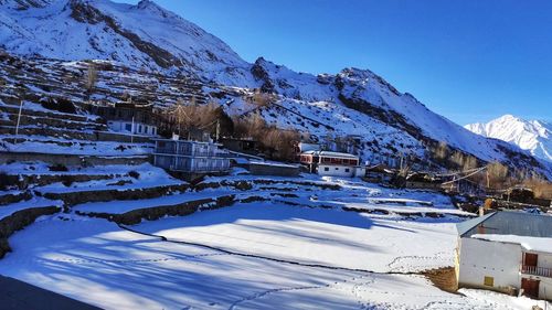 Snow covered buildings by mountain against sky