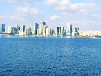 Sea by cityscape against sky