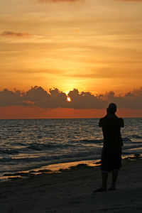 Rear view of silhouette man standing on shore at beach