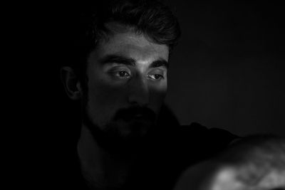 Close-up portrait of young man against black background