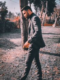 Side view of young man standing on land against sky