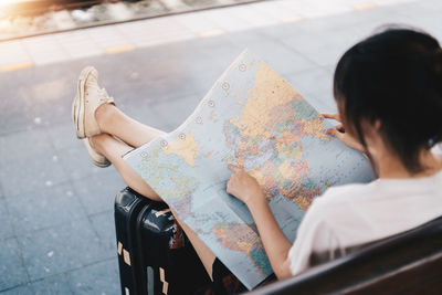 High angle view of woman sitting with map at railroad station