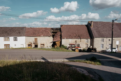 Road by buildings in city against sky