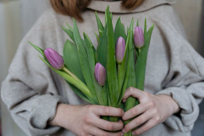 Close-up of a young woman holding a bunch of pink tulips