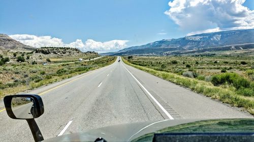 Road by mountains against sky