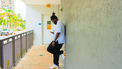 Side view of young man leaning against wall