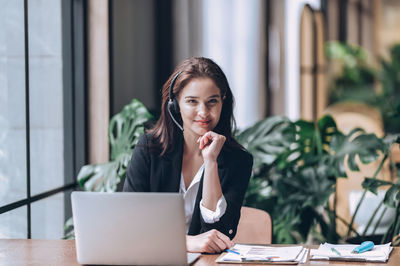 Confident businesswoman wear headset using laptop watch webinar meeting online at desk