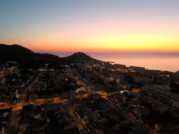 High angle view of townscape by sea against romantic sky