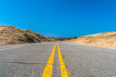 Surface level of road against clear blue sky