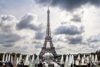 Low angle view of eiffel tower in city against cloudy sky