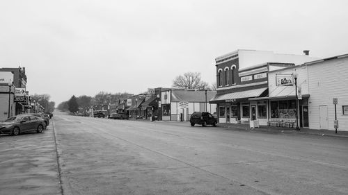 Cars on street by buildings against sky in city