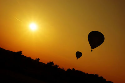 Silhouette hot air balloons against sky during sunset