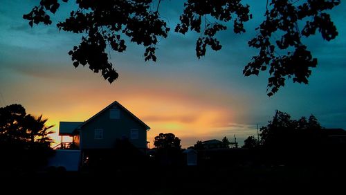 Silhouette houses against sky during sunset