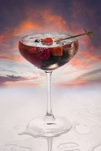 Close-up of wineglass on table against sky during sunset