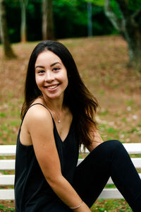 Portrait of smiling young woman sitting on bench