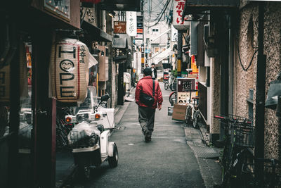 Rear view of people walking on street amidst buildings in city