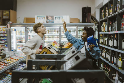 Playful couple having fun while doing shopping at supermarket