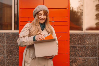 Portrait of young woman standing against wall