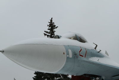 Airplane flying over snow against clear sky