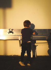 Rear view of boy standing against wall