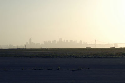 Scenic view of field against cityscape and sky