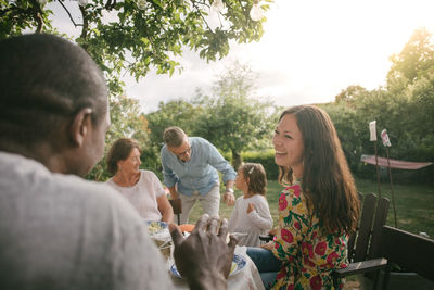 Rear view of people sitting on landscape against trees