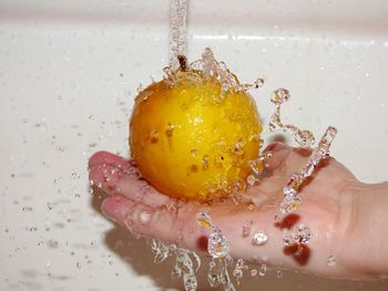 Close-up of hand cleaning orange in sink