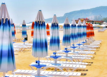 Row of chairs on beach against blue sky