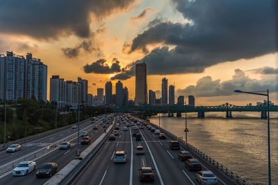 Panoramic view of city street and buildings against sky during sunset