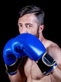 Close-up of man wearing mask against black background